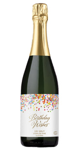 Bottle of 'Birthday Wishes' sparkling wine with a glass of champagne on a white background