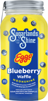 Mason jar of Sugarlands Shine Eggo Blueberry Waffle Moonshine with blueberries on a yellow background