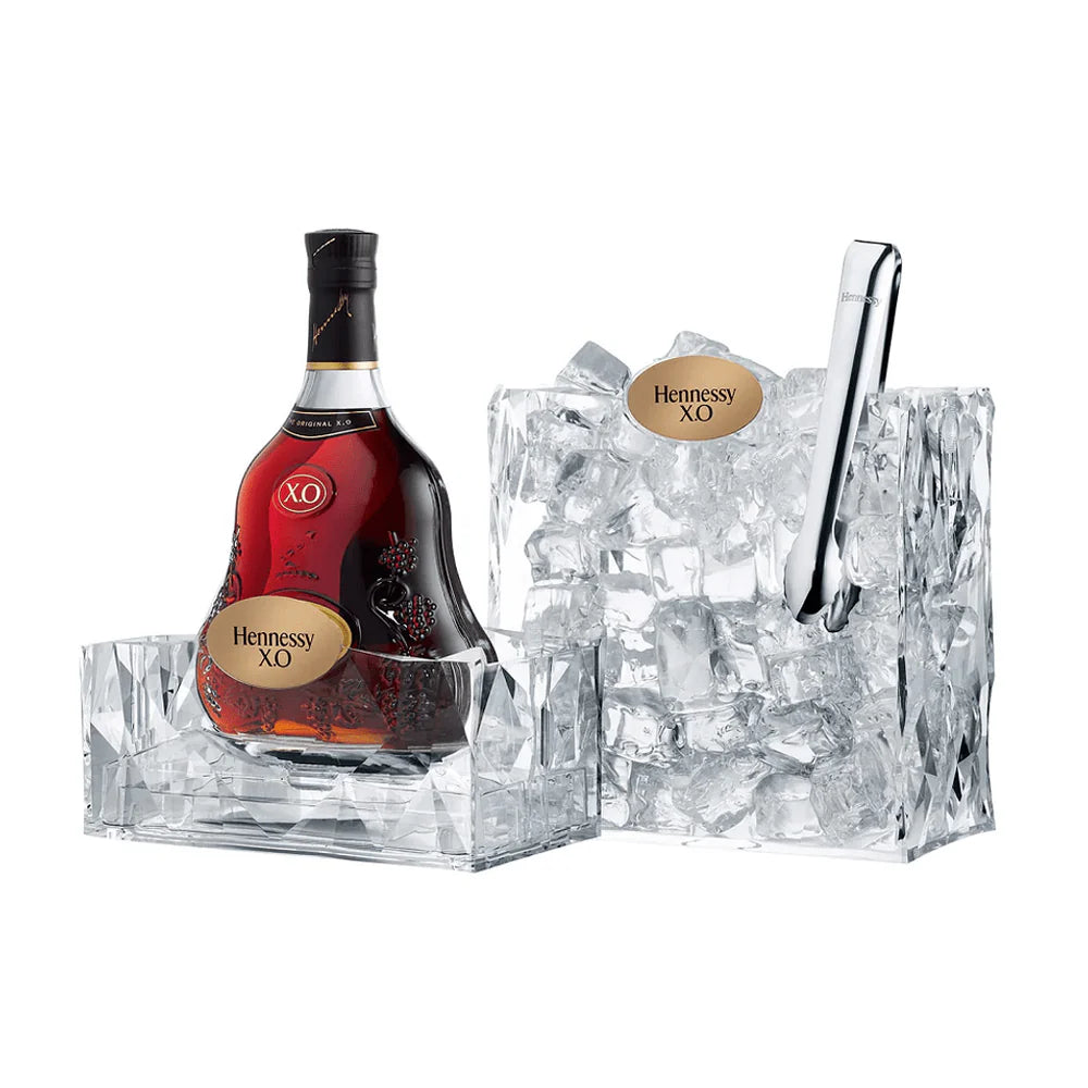 Hennessy XO cognac bottle with ice cubes and a silver scoop on a white background